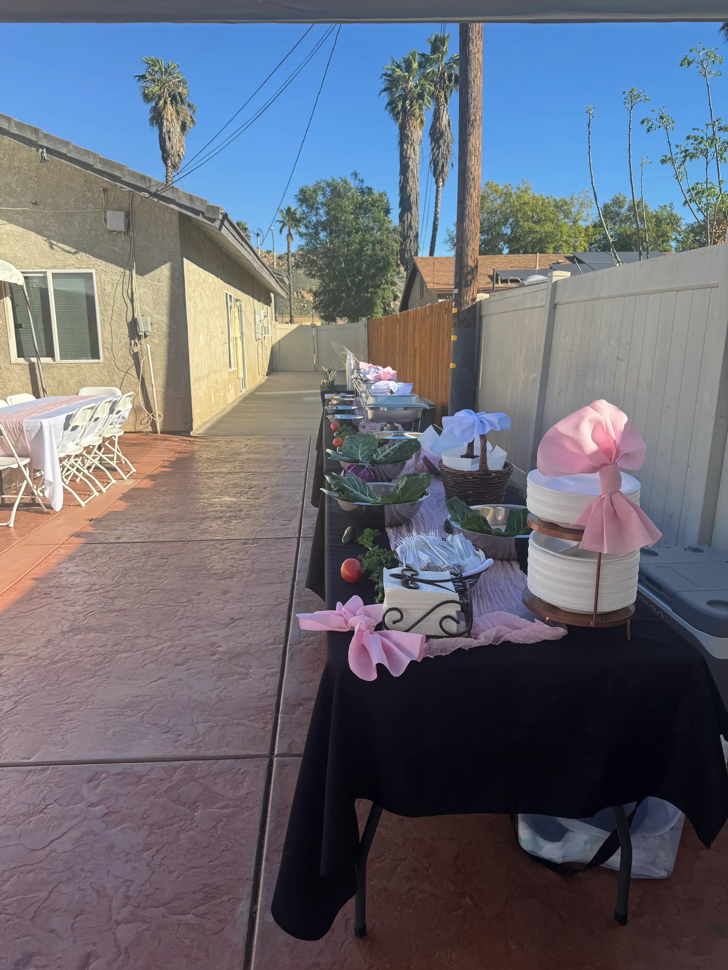 Long Tacos V outdoor buffet table with black tablecloths, pink ribbon accents, and fresh-vegetable garnishes