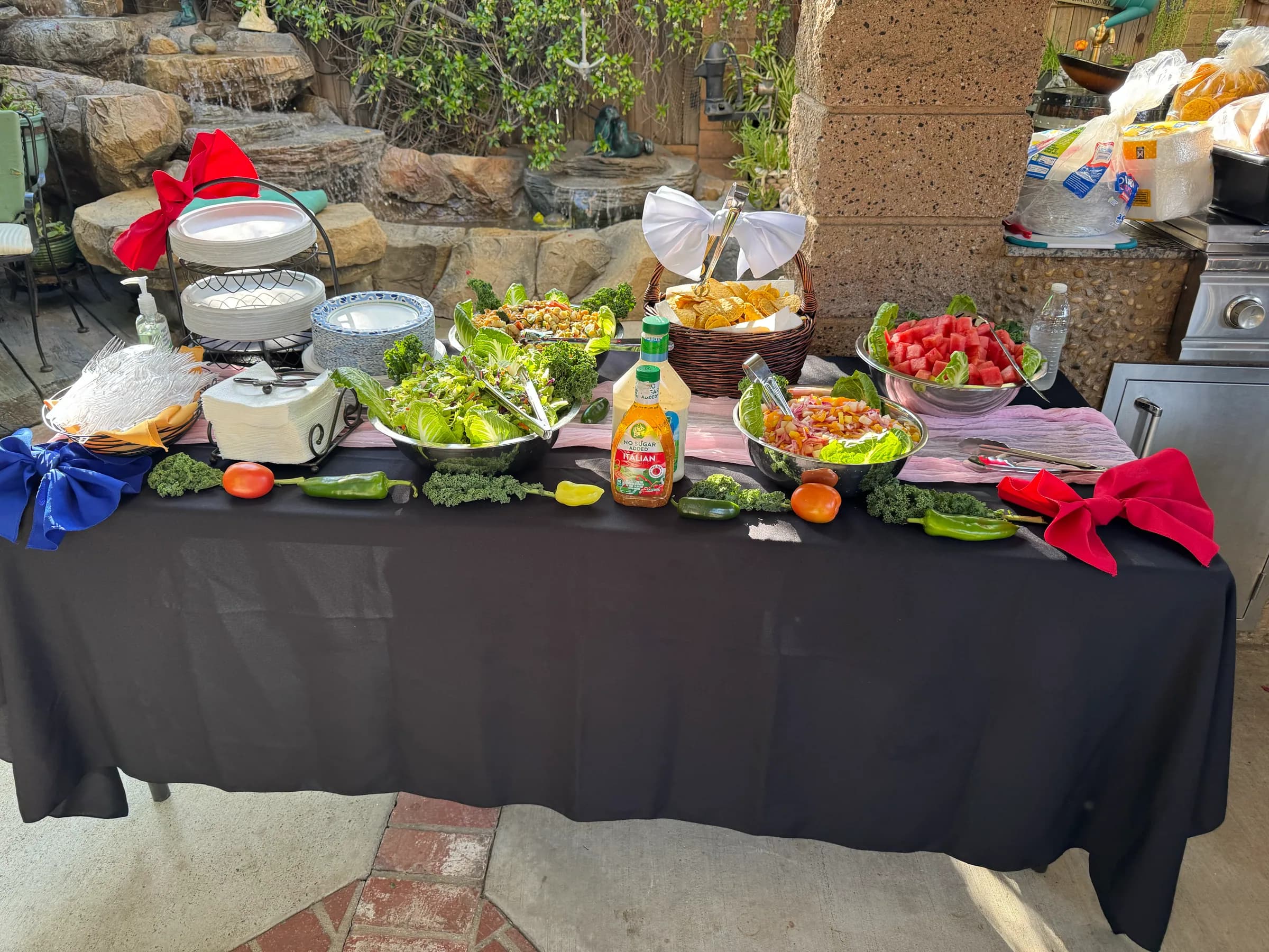 Tacos V sides buffet with green salad, pasta salad, fruit, and chips at an outdoor catering event